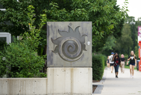 Fireball statue outside with students walking in the distance